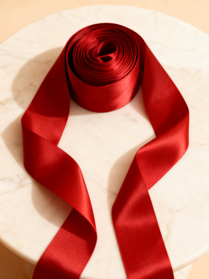 Reine satin ribbon rolled up from above with sheen gradient on marble